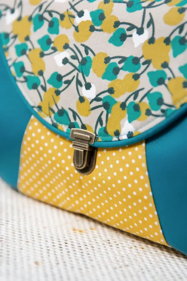 Sac besace Mia zoom sur tissus imprimés turquoises et moutarde et attache cartable rétro