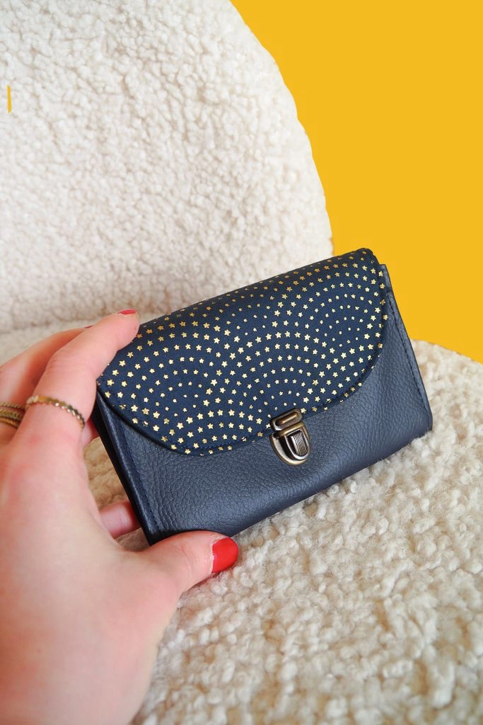 Porte-monnaie artisanal Céleste bleu nuit et doré posé sur fauteuil, création Claire Rainette.