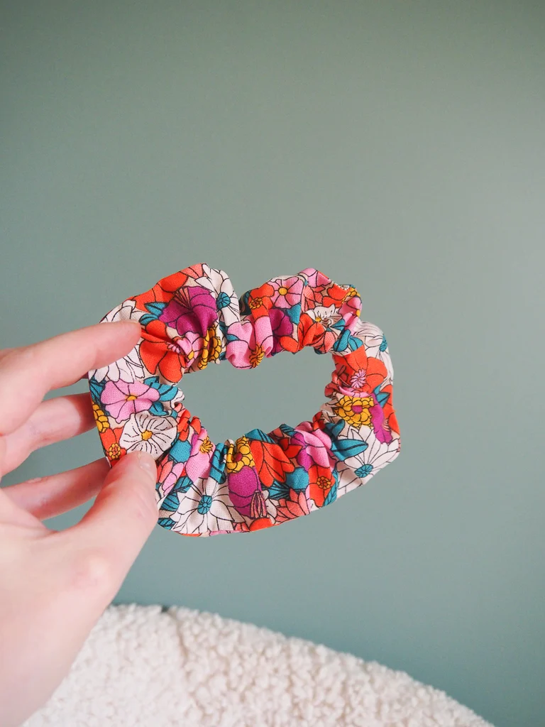 Chouchou cheveux fait main Luz en tissu fleuri coloré porté en queue-de-cheval